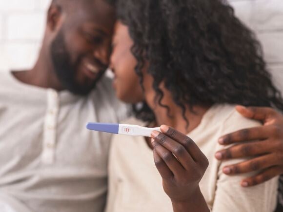 Couple hugging while holding a positive home pregnancy test