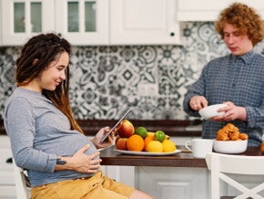 Pregnant woman looking at iPad with man in the kitchen