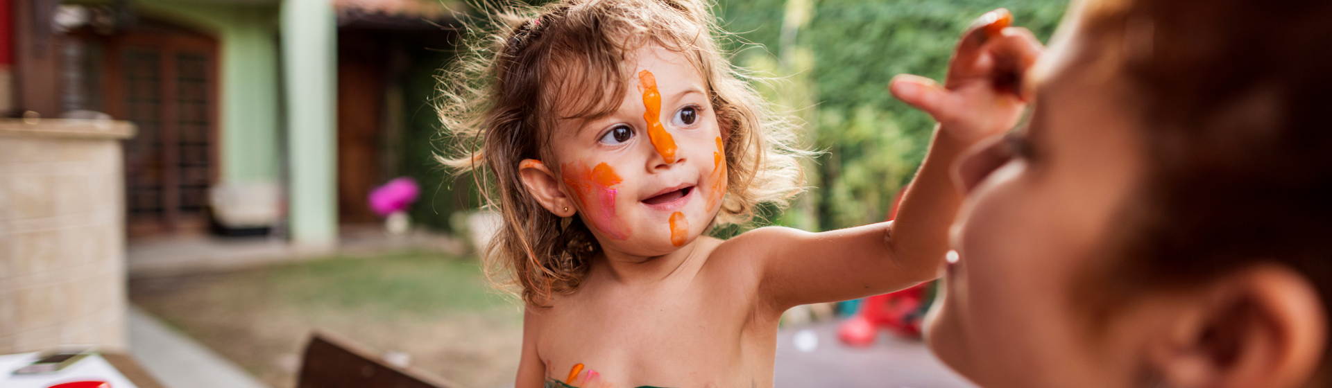 Preschooler with painted face painting mothers face